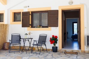 An outdoor seating area with two chairs, a table, and a potted plant with red flowers. - Apartment 'Breathing' with Mountain View, Wi-Fi, and Air Conditioning (Virós)