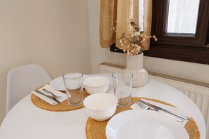 A dining table set with white plates, bowls, glasses, and cutlery, with a woven placemat and a vase with dried flowers. - Apartment 'Breathing' with Mountain View, Wi-Fi, and Air Conditioning (Virós)