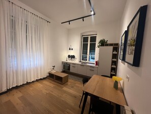 A compact kitchen with a window, a sink, a small oven, and a dining area with a table and chairs.