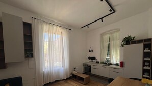 Una cocina compacta con horno integrado, un lavamanos y una pequeña encimera. Hay una zona de comedor con una mesa y sillas de madera.