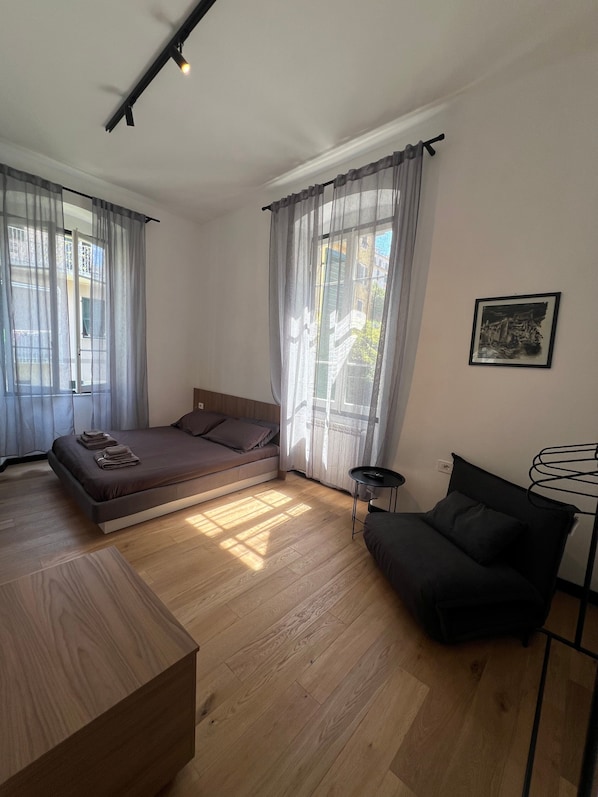 A modern bedroom with a bed, a small sofa, a wooden table, and a picture on the wall.