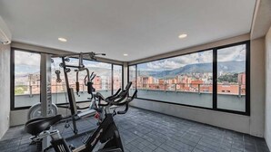 A spacious balcony with exercise equipment, large windows offering a city view. - Charming 1-bedroom apartment with WiFi, AC in delightful Medellín (Medellín)