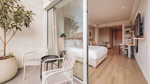 A modern hotel room with a glass door leading to a balcony, a bed with white bedding, a small table, and a potted plant. - Charming 1-bedroom apartment with WiFi, AC in delightful Medellín (Medellín)