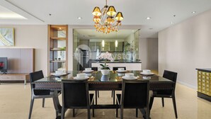 A modern dining area with a glass table, black chairs, and a chandelier. - Corinna by Kozystay - Senayan (Jakarta)