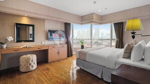 A modern hotel room with a large bed, a desk, a TV, and a city view. - Corinna by Kozystay - Senayan (Jakarta)