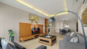 A modern living room with a flat-screen TV, a wooden entertainment unit, a coffee table, and a sofa. - Corinna by Kozystay - Senayan (Jakarta)