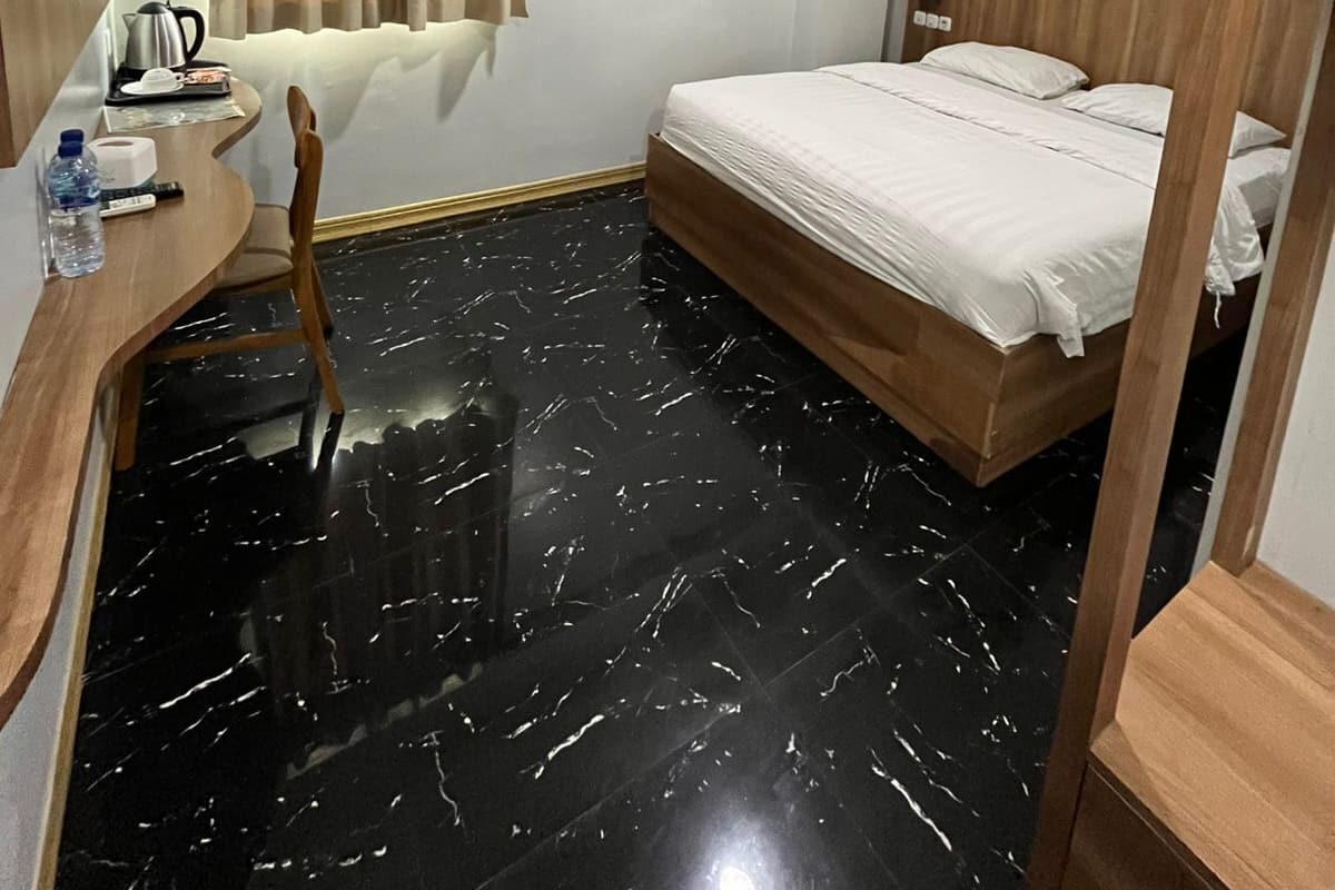 Habitación de hotel con cama, escritorio con silla, televisor de pantalla plana, cortina de ducha y cabecero de madera.