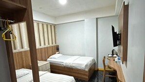 A hotel room with two beds, a wooden desk, a chair, a hanging coat rack, and a small scale.