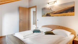 A bedroom with a wooden bed, a door, and a wall-mounted picture. - Apartment 'Sonnblick' with Mountain View, Shared Garden and Wi-Fi (Laives)