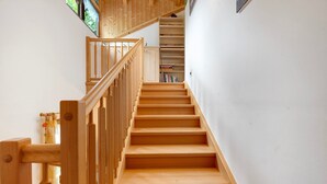 A wooden staircase with a handrail, leading to a landing with bookshelves. - Apartment 'Sonnblick' with Mountain View, Shared Garden and Wi-Fi (Laives)