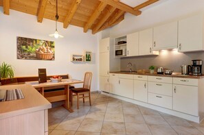 Une cuisine moderne avec des meubles blancs, une table à manger et un luminaire suspendu.
