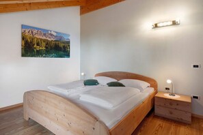 Un lit en bois avec une tête de lit, une table de chevet avec une lampe et un luminaire fixé au mur.