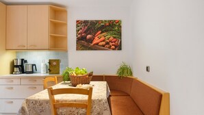 Una cocina con armarios de madera, una mesa de comedor con mantel floral y un banco.