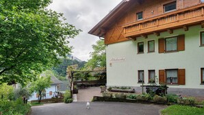 A building with a sign 'Altbernerhof' and a paved driveway leading to a gate.