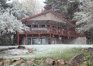 Un bâtiment à deux étages doté d’un balcon, entouré d’arbres couverts de neige et d’une zone herbeuse.
