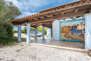 Uma área externa coberta com telhado de azulejos, um mural e um caminho de cascalho.