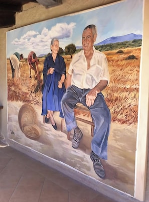 Et mural med en mand og en kvinde i et mark, et hjul, og et landskab med bjerge.