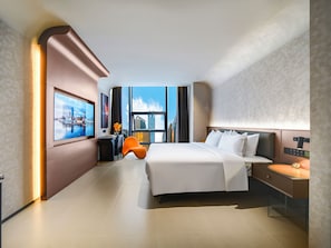 Une chambre d’hôtel moderne, dotée d’un grand lit, d’un bureau, d’une chaise et offrant une vue sur la ville par la fenêtre.