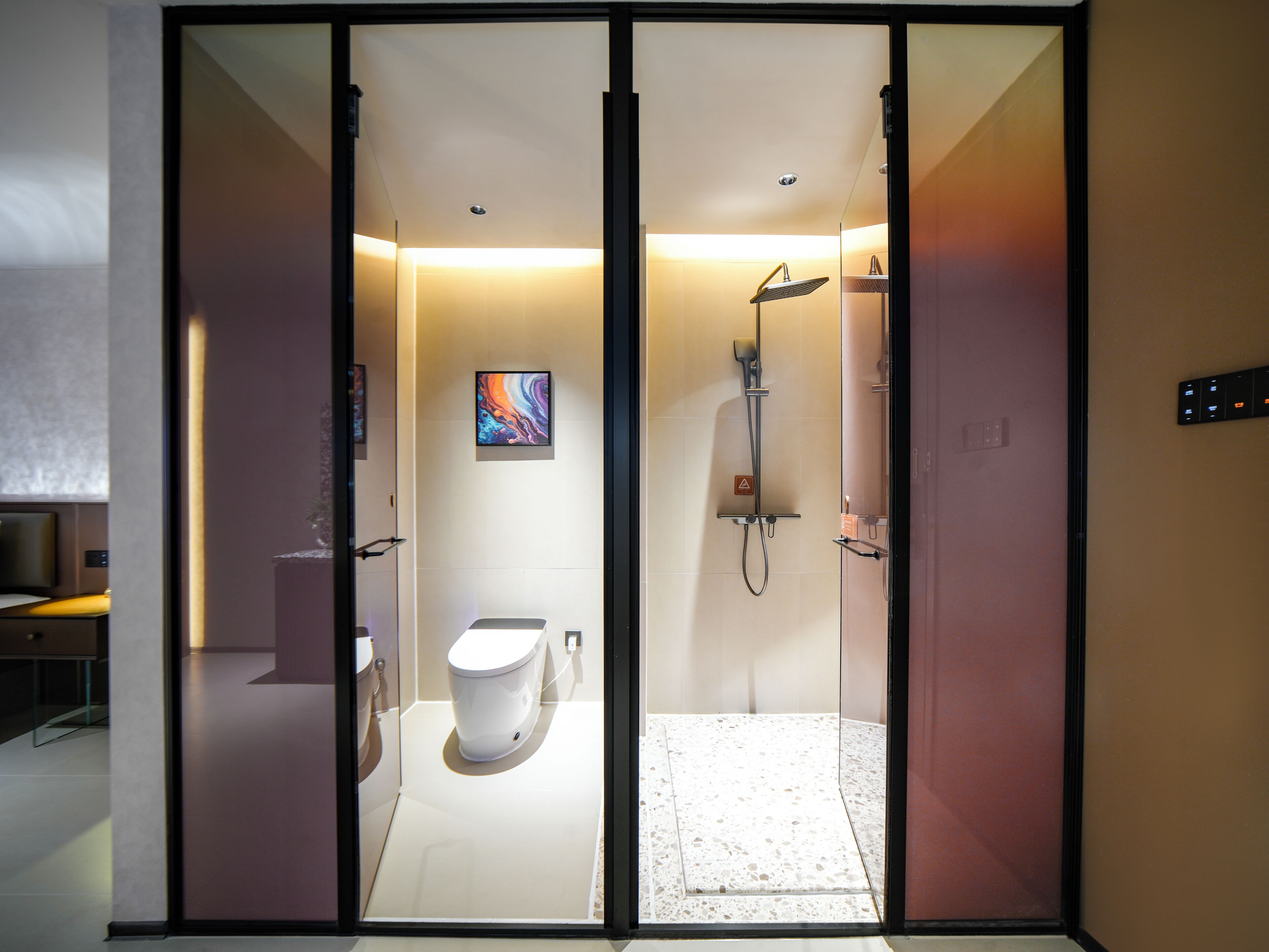 A modern bathroom with a toilet, shower, and a glass partition.