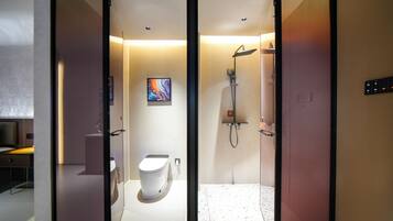 A modern bathroom with a toilet, shower, and a glass partition.