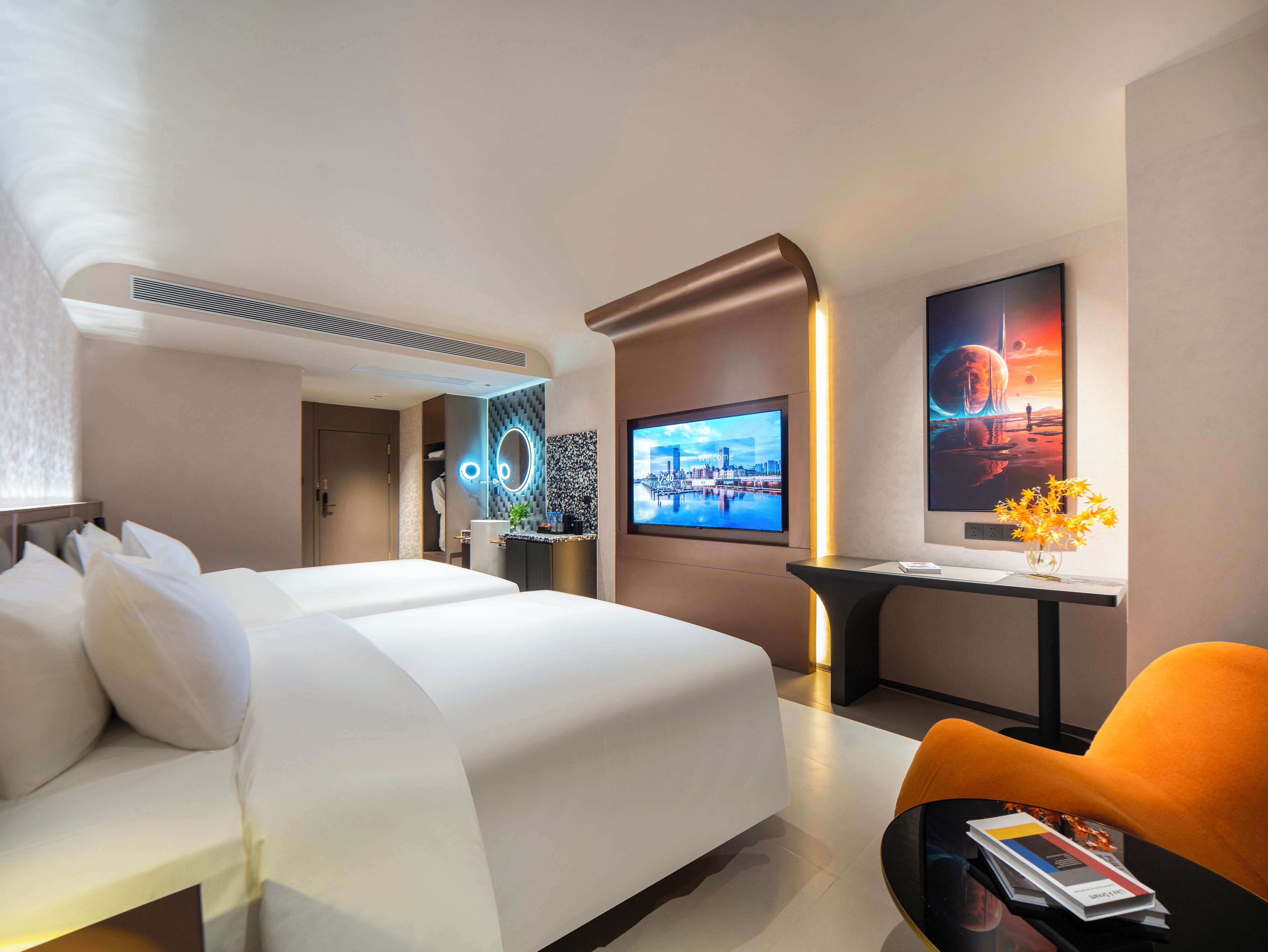 A modern hotel room with a large bed, a desk with a computer, a TV, and a decorative vase.