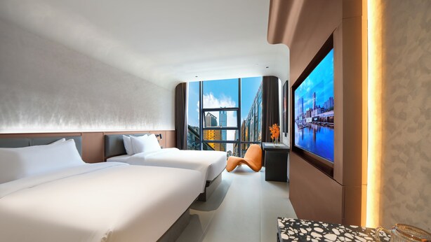 A modern hotel room with two beds, a large TV screen, and a view of the cityscape. - chongqinglangxidujiajiudian (Deyang)