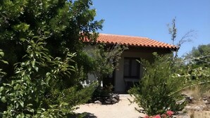 Una casa con techo de tejas rojas, camino de grava y vegetación circundante.