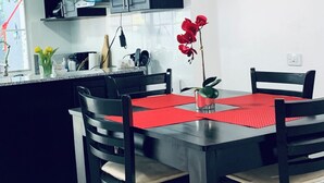 Una cocina moderna con armarios oscuros, un microondas y un comedor con un mantel individual rojo.