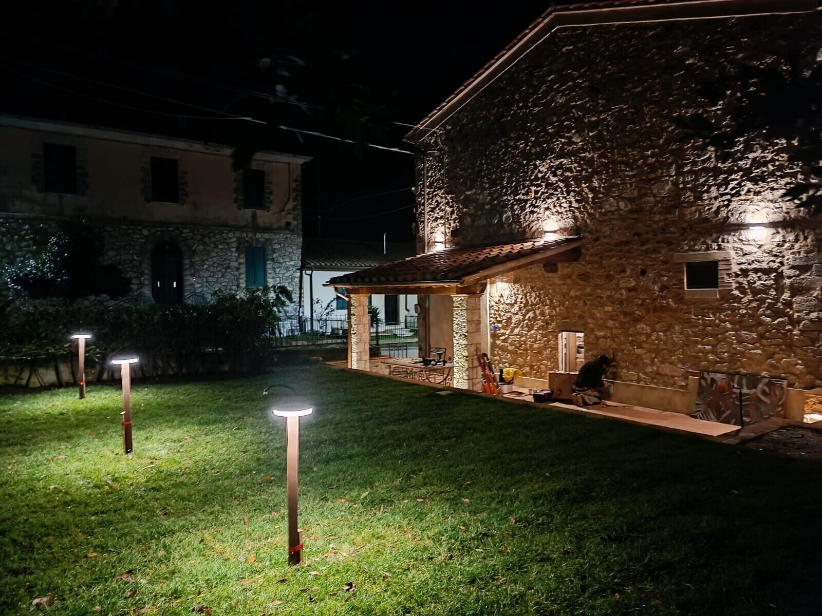 A stone building with a covered patio and a lawn.