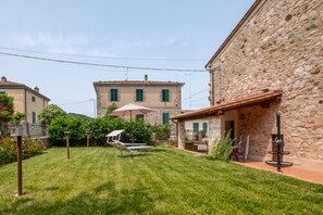 Un bâtiment en pierre doté d’un jardin, d’une pelouse et d’un petit espace extérieur aménagé avec des sièges.