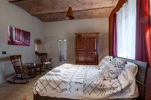 Une chambre à coucher avec un lit, des fauteuils à bascule en bois, une table à manger et une grande armoire.