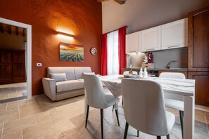 A modern kitchen with white cabinets, a dining table with chairs, and a red curtain.