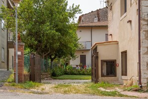 A narrow street with buildings, a tree, and a gate.