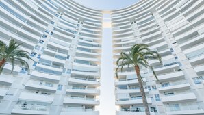 Un moderno edificio de gran altura con un diseño simétrico, que cuenta con varios balcones y un atrio central.