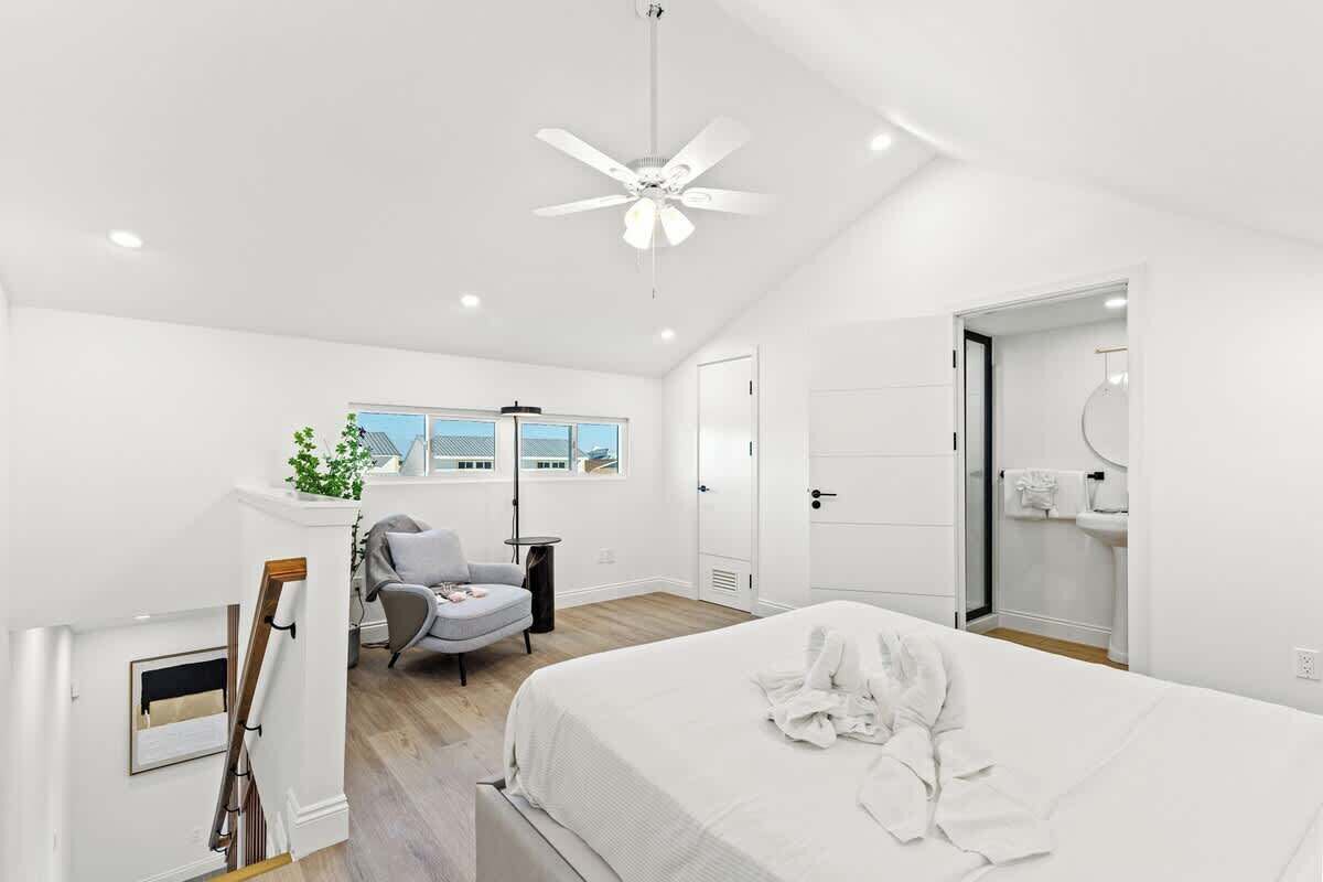 Une chambre moderne avec un grand lit, un ventilateur de plafond, un bureau et une chaise.