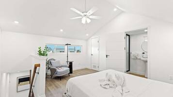 Une chambre moderne avec un grand lit, un ventilateur de plafond, un bureau et une chaise.