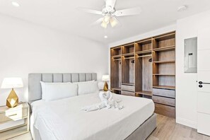 Een slaapkamer met een bed, nachtkastjes, een plafondventilator, een kledingkast en een deur.
