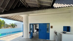 A covered outdoor area with a pool, a blue door, and a view of the pool. - Bali Bio Villas (Ungasan)