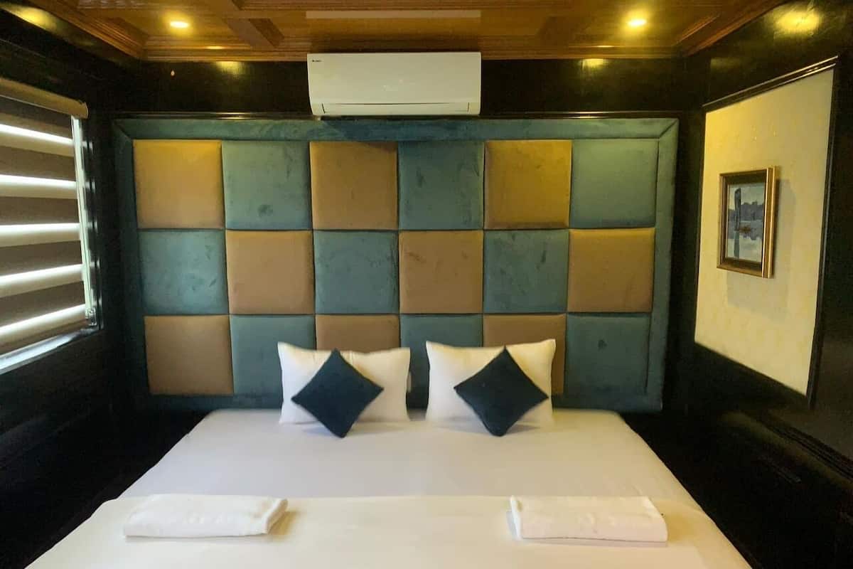 Una camera d'albergo con un letto grande, una testata geometrica e un quadro appeso alla parete.