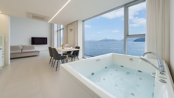 Una habitación de hotel moderna con una bañera grande, un comedor y un sofá.