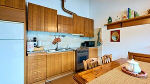 A kitchen with wooden cabinets, a refrigerator, a stove, and a dining table with chairs.