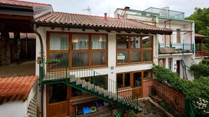 A two-story building with a balcony, a staircase, and a small garden area.