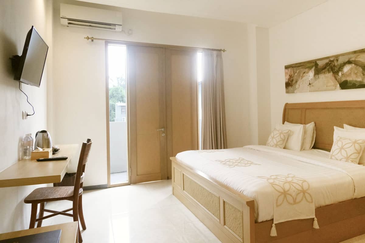 Een hotelkamer met een bed, een bureau, een stoel, een televisie en een schilderij aan de muur.