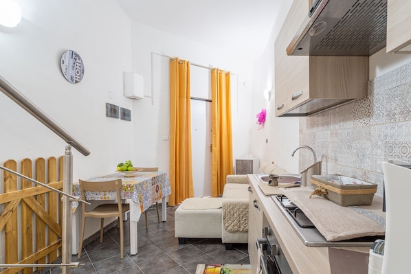 A compact kitchen with a dining area, a small table, and a sofa.