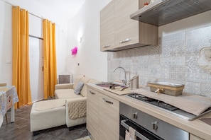 A compact kitchenette with a stove, sink, and wooden cabinets.