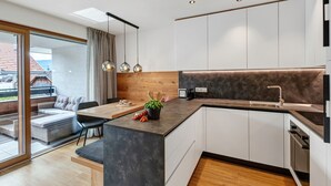Une cuisine moderne dotée d’un îlot central intégré, d’un coin repas avec un banc et d’une porte-fenêtre coulissante donnant sur un patio.