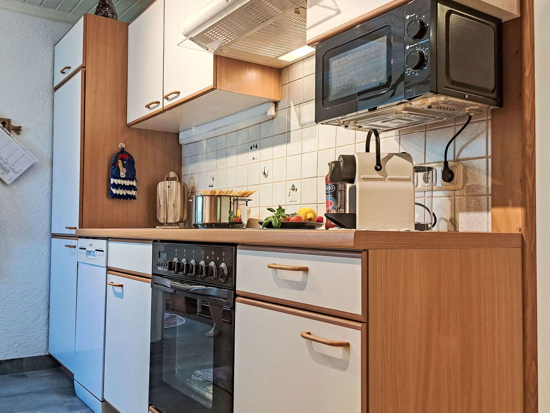 Cozinha compacta com micro-ondas, forno e máquina de café expresso.
