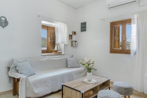 A room with a sofa, a small table with a vase, and a window with curtains.