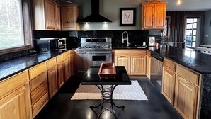 Una cucina moderna con mobili in legno, un piano di lavoro nero e un'isola centrale.