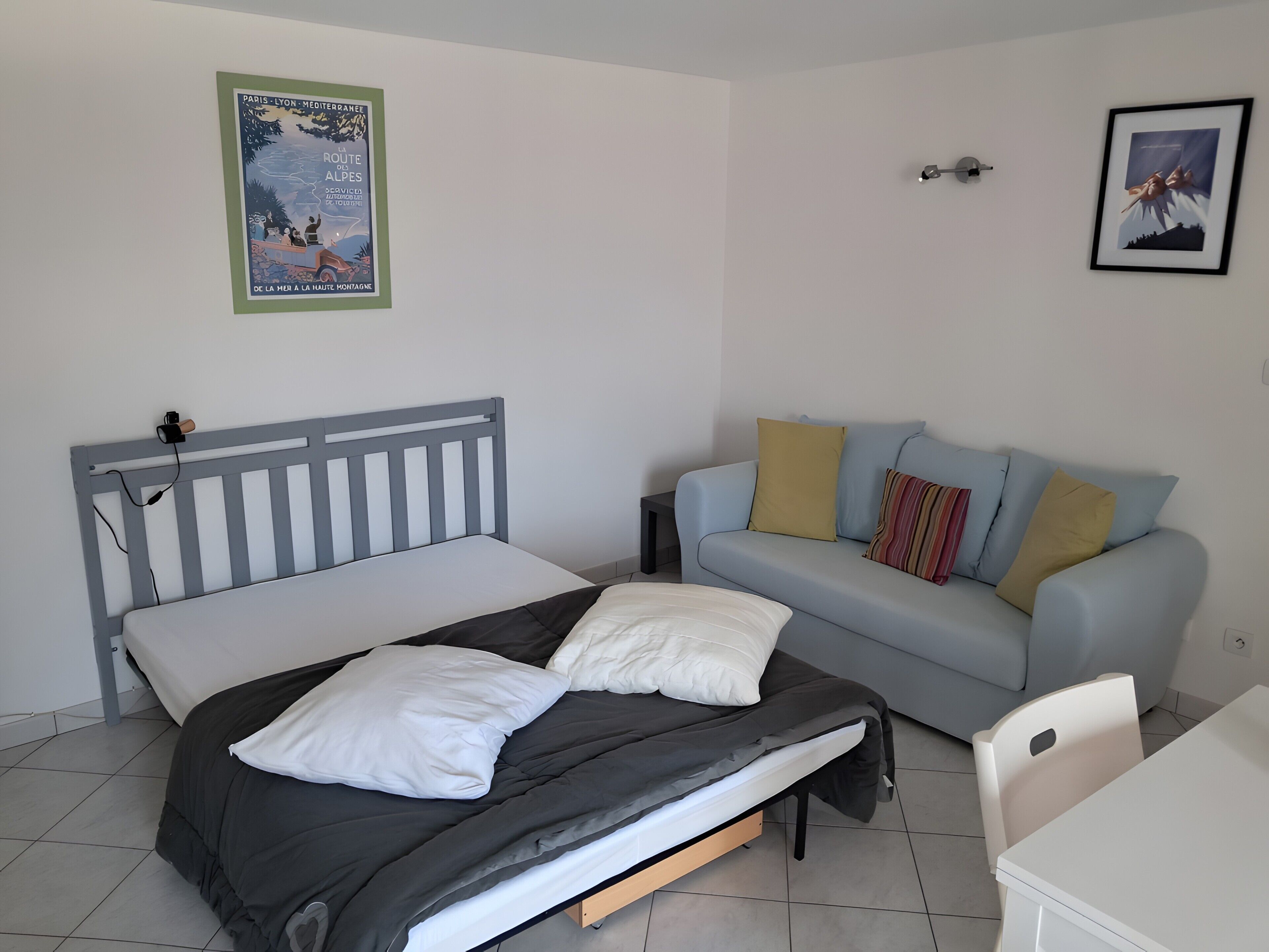 Een slaapkamer met een bed, een bank, een stoel en een klein tafeltje.